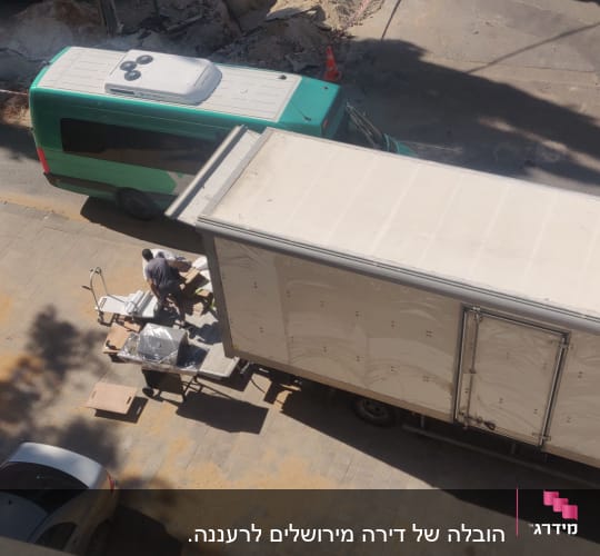 אנשים מעמיסים חפצים על משאית גדולה ברחוב